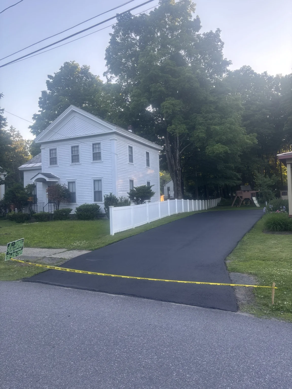 Freshly sealed driveway beside white home
